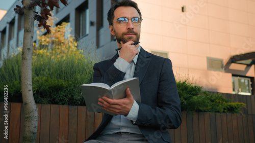 Thoughtful pensive man Caucasian businessman business coach in city write notes in notebook university professor writer thinking writing ideas at paper notepad smiling prepare for class lesson outside