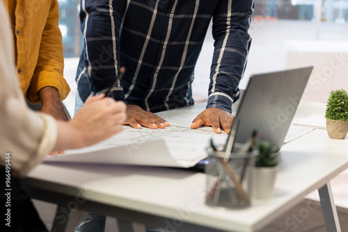 Entrepreneur and real estate agents collaborate on a corporate office planning session, discussing blueprints and investment strategies for leasing or renting a new urban office space. Close up.