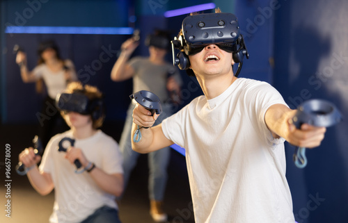 Man in virtual reality glasses and with joystick plays exciting shooter game with friends. Technology simulation hi-tech videogame concept