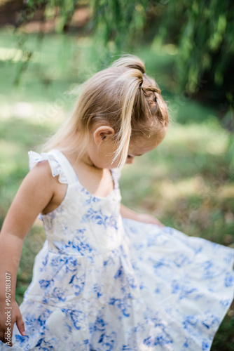 Joyful Little Girl Twirling Under a Tree in a White Floral Dress