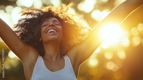 A joyful woman with curly hair celebrates life outdoors at sunset in a vibrant natural setting