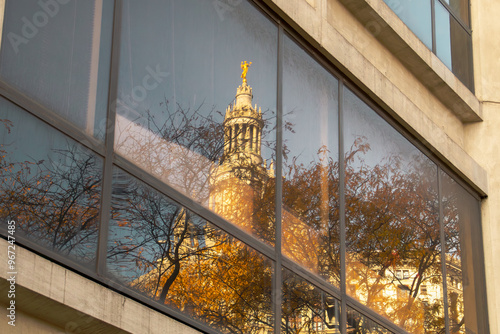 Reflejo en una ventana del edificio municipal David N. Dinkins de Manhattan, Nueva York, EE.UU. Reflejo de un árbol en otoño y detalles de la cúpula, la estatua dorada de la Fama Cívica.