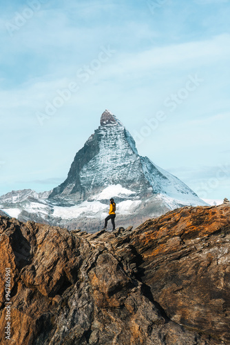 A woman standing on top of rocky mountain with Matterhorn mountain on sunny day at Switzerland