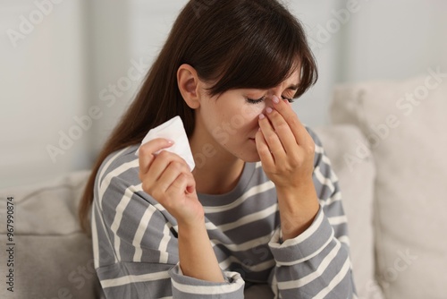 Woman with napkin suffering from sinusitis on sofa at home