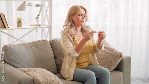 Pregnancy fail. Upset woman. Disappointment regret. Hopeful lady looking to result of medical test sitting light room interior.