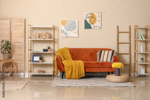 Cozy sofa with plaid, cushion and vase with narcissus flowers in living room