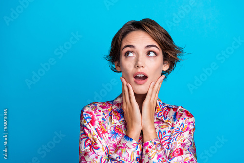 Photo of excited adorable girl wear flowers print clothes two arm touch cheeks special news empty space isolated on blue color background