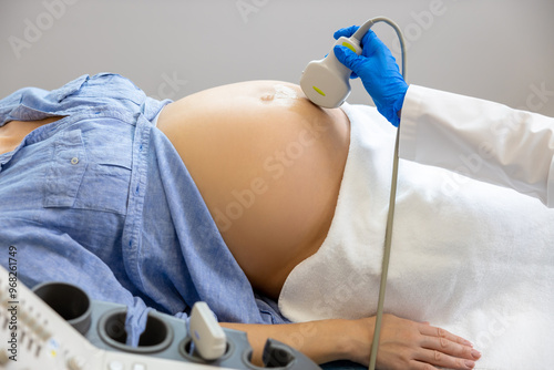 Pregnant woman lying on a couch in clinic while ultrasonography