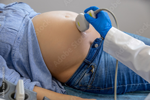 Close up of doctors hand with sensor doing ultrasonography to a pregnant woman