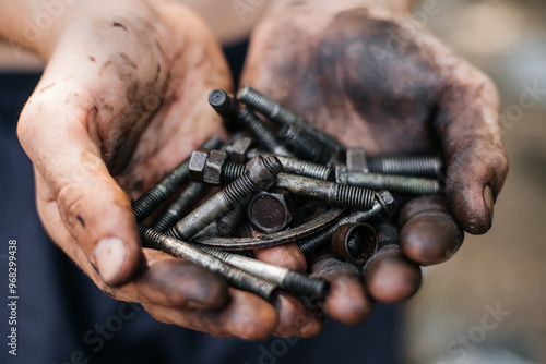 Worker holds dirty old bolts in mazut in his hands. Concept of car repair, repair