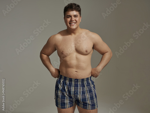 Attractive young man with a curvy, fuller figure, confidently posing in boxer shorts