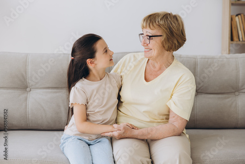 Cheerful cute granddaughter kid and happy grandma hugging with love, tenderness, affection, Grandmother embracing grandchild, enjoying family relationship.