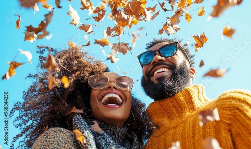 Afro couple throwing autumn leaves, walking in a park, and having fun