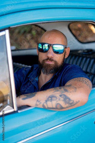 Man with beard and sunglasses sitting in a blue car