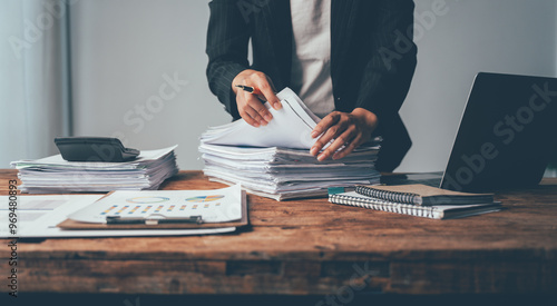 Overwhelmed by Paperwork: A businesswoman grapples with a towering stack of documents, her desk cluttered with the tools of a demanding profession, evoking the stress of deadlines and administrative o