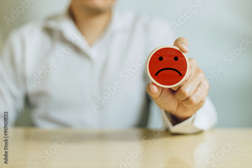 Service rating, satisfaction and negative feedback. A man hold wooden cube with bad face emoticon give a one star rating indicates the lowest level of satisfaction with the service