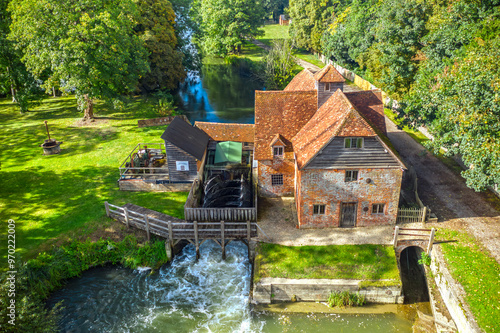 An old public common non private aerial view of a river with a watermill , lock system and a weir