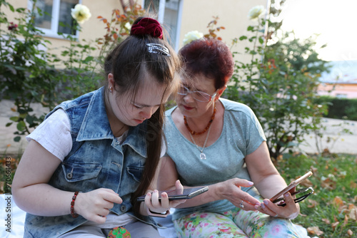 Mother and daughter with Down syndrome walking and using smartphone.