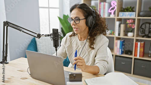 Hispanic woman records podcast in a cozy studio with modern equipment