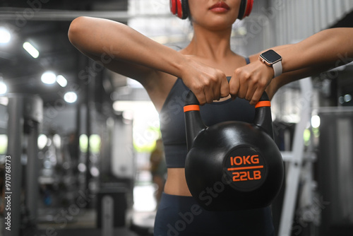 Motivated female athlete exercising with kettle bell at gym. Fit, sports and healthy lifestyle concept