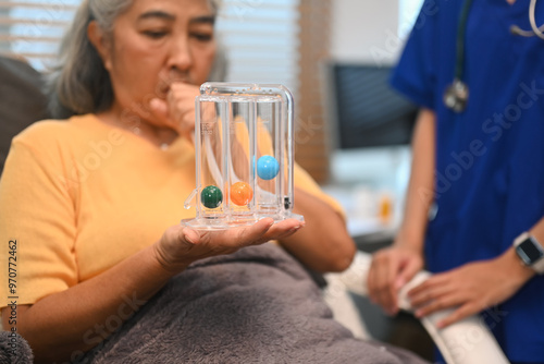 Mature woman using a spirometer to help patients to improve the functioning of lungs under healthcare professional