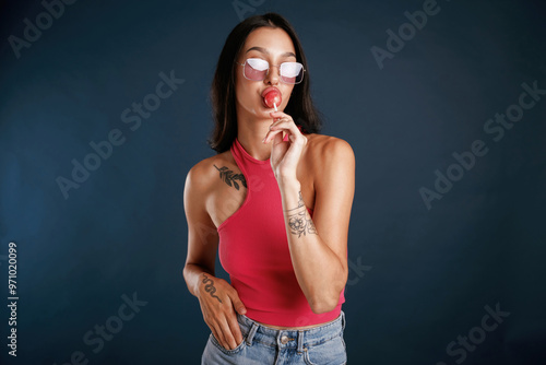 Red lollipop is in the hand. Beautiful young woman is against background