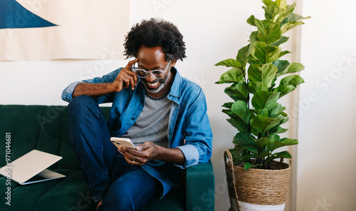 Mature man smiling and reading a message from his mobile phone at home