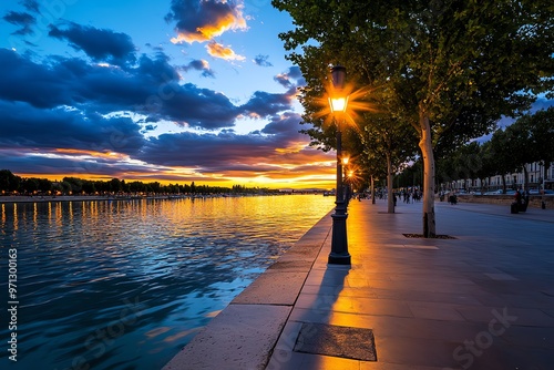 A serene moment by the RhÃ´ne River, with locals enjoying an evening stroll along the waterfront as the sun sets over Arles