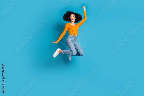 Full length photo of lovely young lady jump excited wave hand dressed stylish yellow garment isolated on blue color background