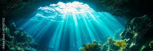 An underwater photograph of the Great Blue Hole, a massive sinkhole off the coast of Belize. The image captures the ethereal beauty of sunlight streaming through the water, illuminating the dark dept