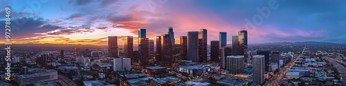 Modern cityscape of Los Angeles City with skyscrapers and highways, Los Angeles river in the background at dusk, illuminated by street lights. A Vincent Thomas bridge connecting two parts of downtown