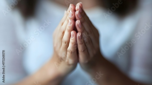 A close-up of hands clasped in prayer, with a soft light illuminating the scene against a plain background