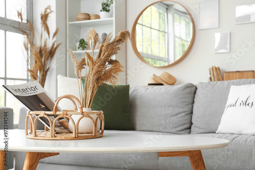 Interior of cozy living room with grey sofa, coffee table and vase of pampas grass, closeup