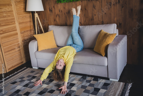 Full size photo of attractive young female lying sofa upside down dressed yellow sweater cozy day light home interior living room