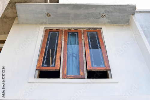 A modern window with a wooden frame and glass panes, partially open to allow natural light and ventilation 