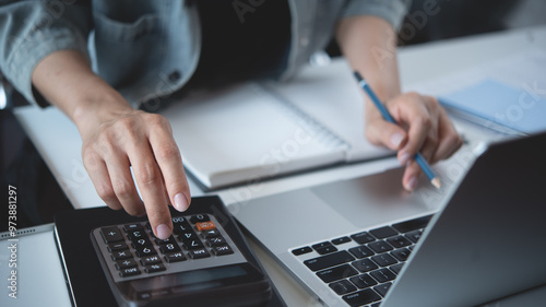 Close up business woman hand using calculator to calculate home finance, accounting with laptop computer on table, budget management, monthly expenses. Doing finance, budgeting and tax calculation