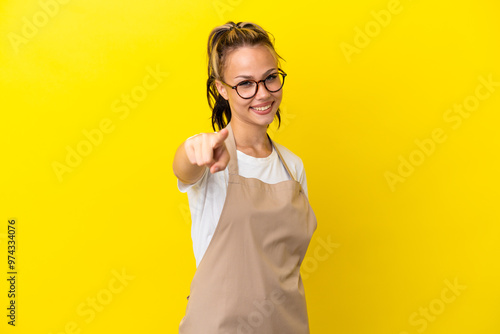 Restaurant waiter Russian girl isolated on yellow background points finger at you with a confident expression