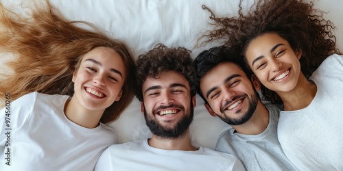 Group of happy friends smiling together on a bed, showcasing friendship and joy in a cozy indoor setting.