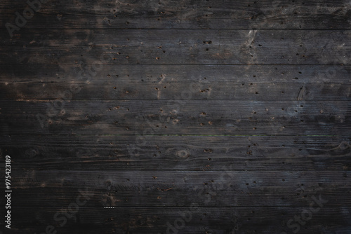 Rustic, dark wood surface aged texture showcases intricate grain patterns. Charred and weathered, planks reveal vintage, earthy warmth, creating natural, organic feel reminiscent of firewood.