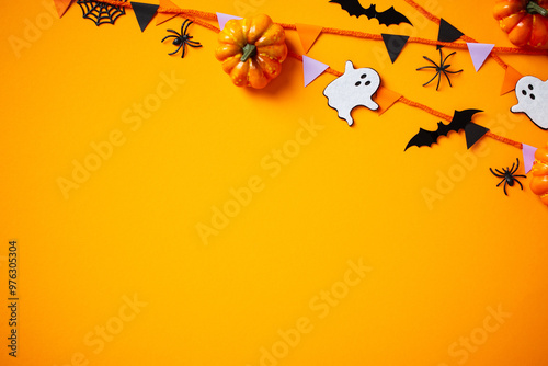 Halloween party decorations, pumpkins, garland, ghosts, spiders, bats on orange background. Happy Halloween holiday greeting card template. Flat lay, top view, copy space.