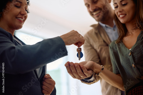 Close up of real estate agent giving new house keys to couple of buyers.