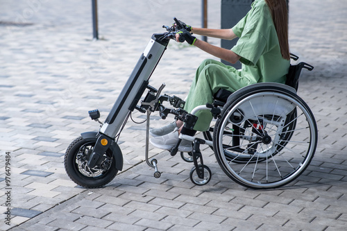 A woman controls a wheelchair using a special manual device. Close-up of female hands on electric handbike. 