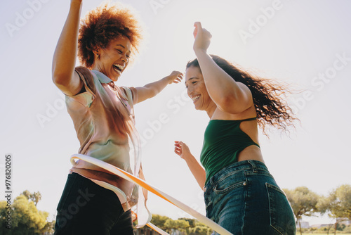 Playful friends having fun with hula hoops during a summer day at the park