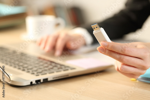 Executive hand holding usb drive using laptop on a desk