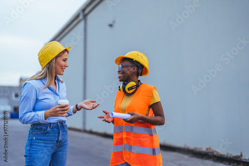 Two Female Construction Workers Discussing Project On Site