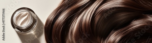 Luxurious brown hair with a smooth texture beside a stylish jar of hair cream, highlighting beauty and hair care.