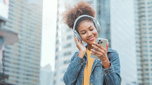 Attractive young African American woman putting headphones and enjoying dancing music on the urban city, Female listening to music, song, podcast, or audiobook.