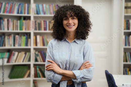 Curly-haired pretty young woman standing on the bookshelves background