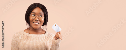 Smiling Black Woman Holding Credit Card Looking Aside Thinking About Something Standing Over Pink Background In Studio. Panorama