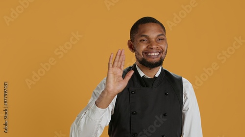 Skilled waiter waving and greeting clients at five star restaurant, working in hospitality industry and catering. Employee server welcoming customers to eat, professionalism. Camera A.